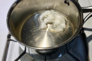 Coconut oil melting in a stainless steel pot