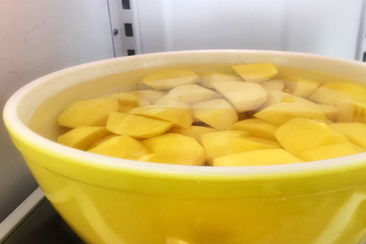 cut up potatoes in a yellow bowl soaking in water