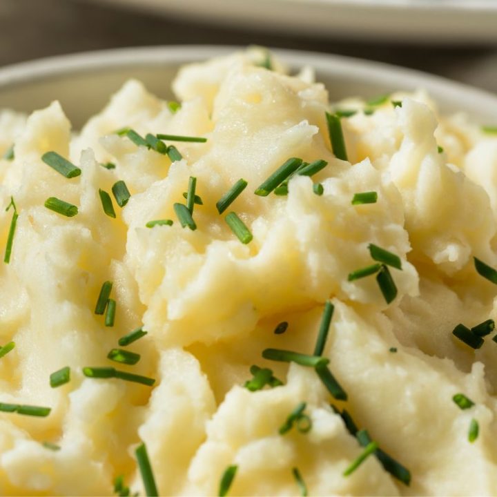 mashed potatoes close up in a bowl with chives on top