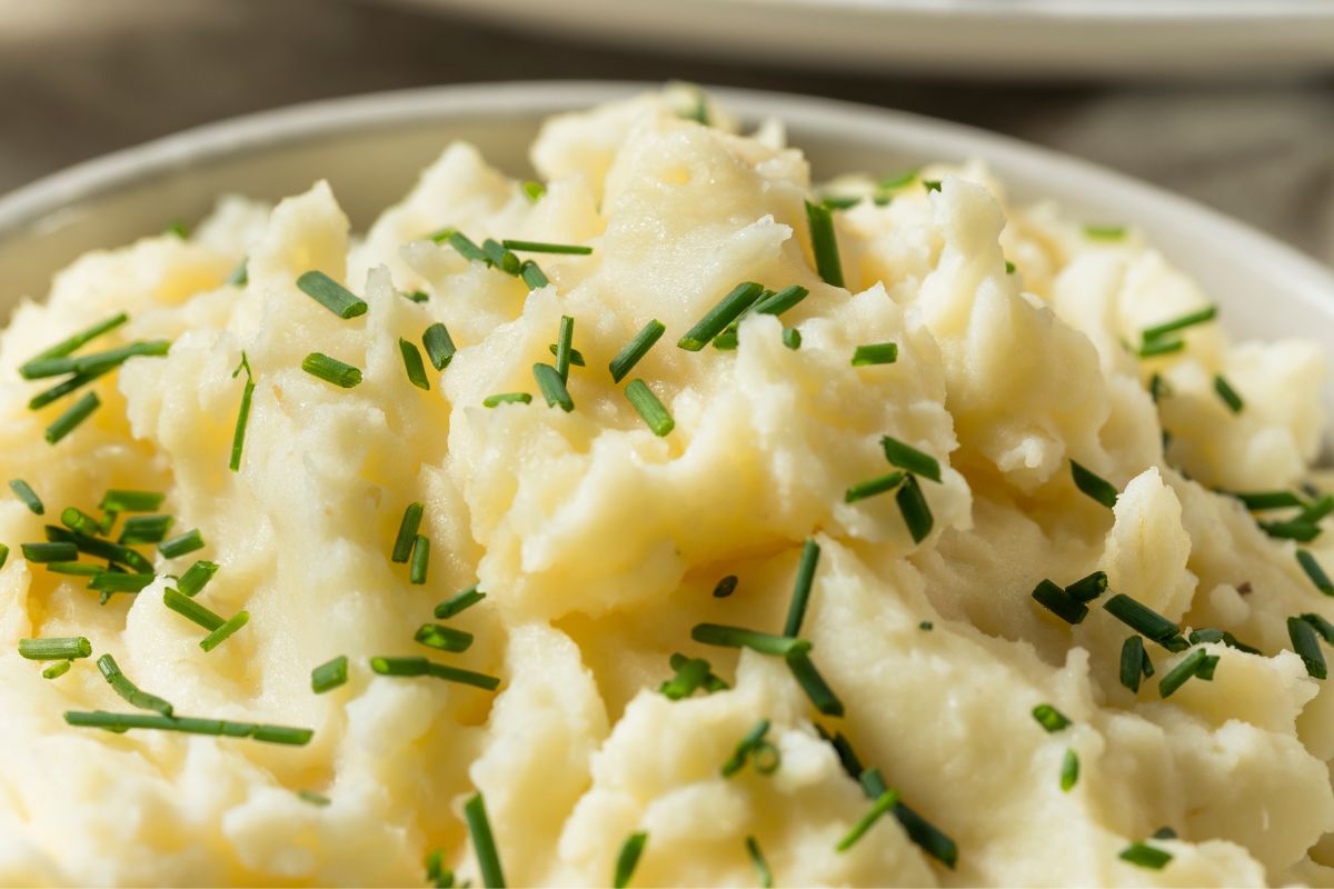 mashed potatoes close up in a bowl with chives on top