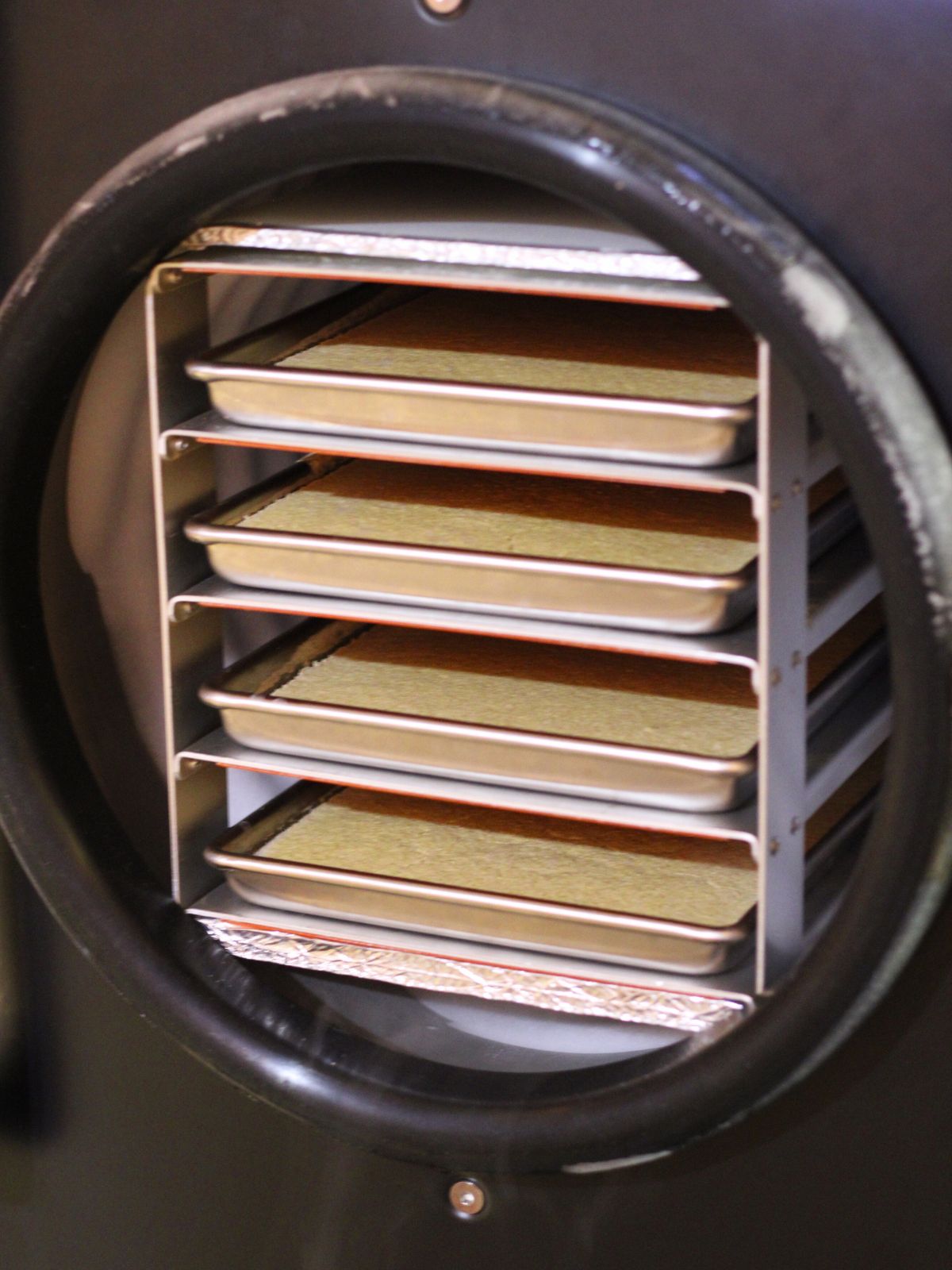 A black freeze dryer with pancake batter on the trays.