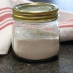 Jar of homemade baking powder with a red and white striped towel.