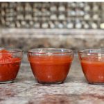 Three glass bowls with red tomato juice, sauce, and paste.